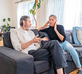 Woman covering her ears with man confused to why